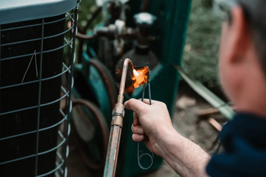 A Denaeyer technician servicing a residential air conditioning system.