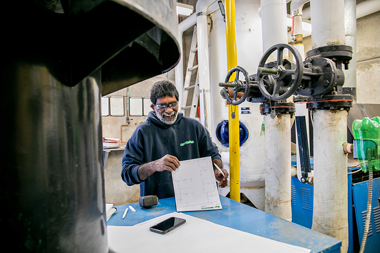Mechanical service professional reviewing plans beside equipment.